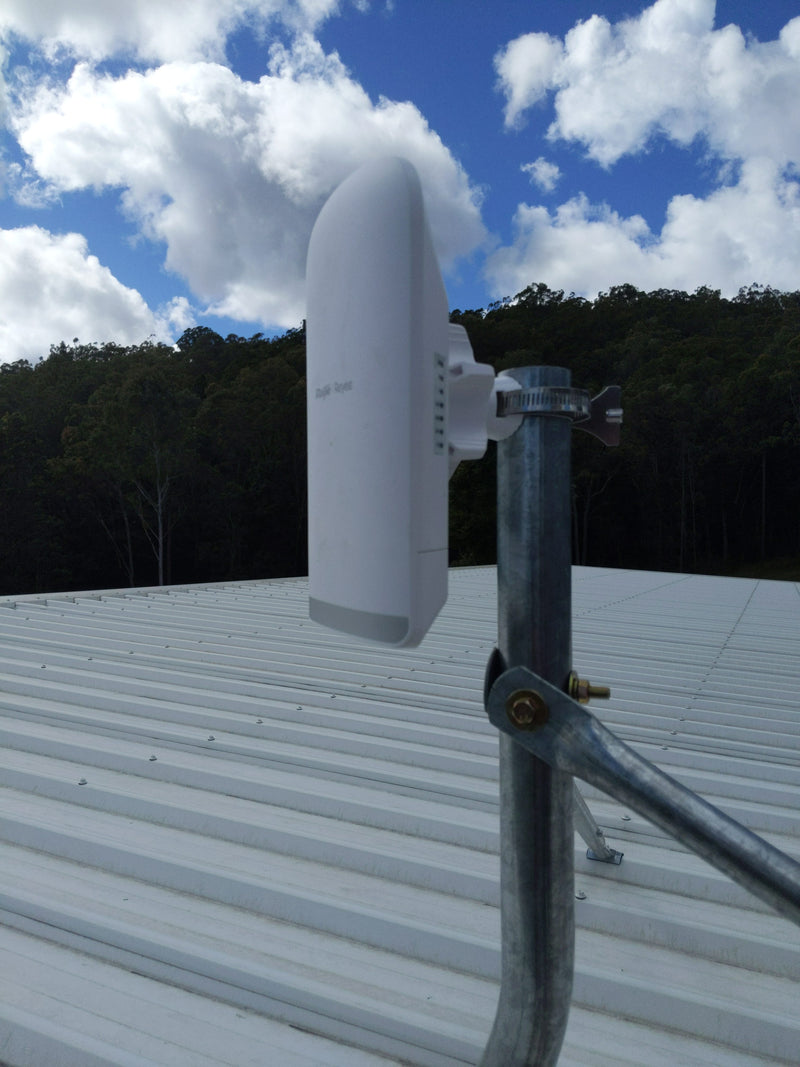 A white wireless network extender device mounted on a galvanized steel pole on a metal roof.